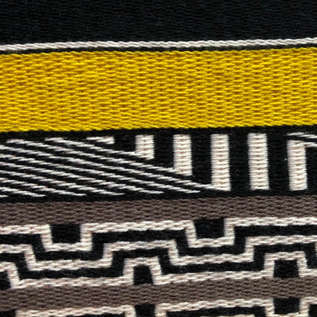 Black, white, and yellow patterns from a detail of a woven robe.