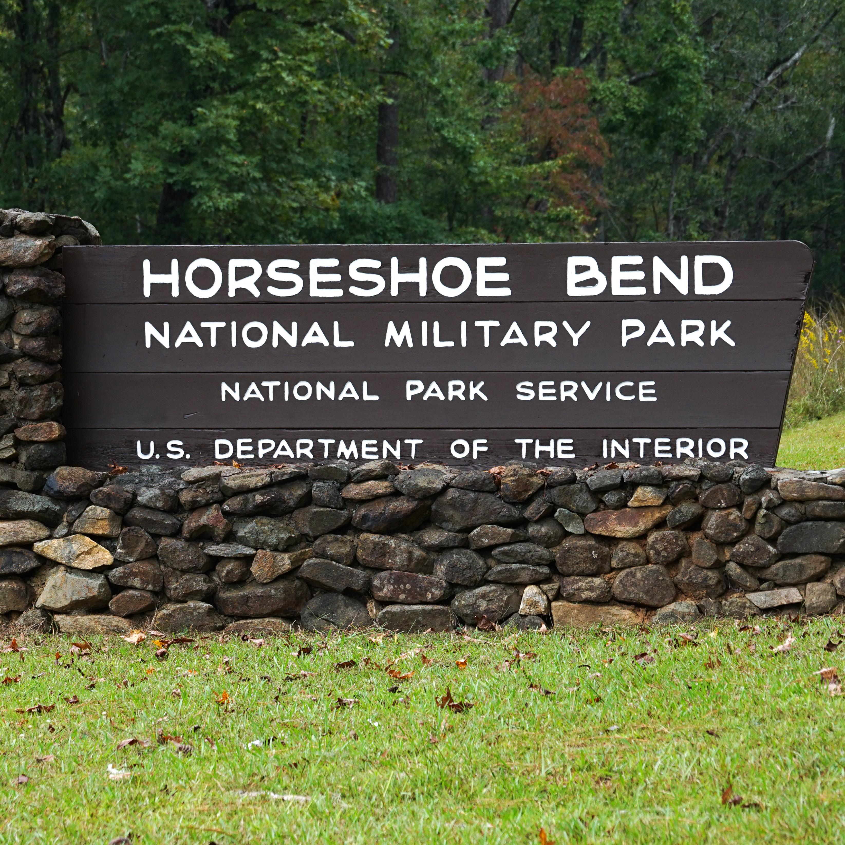 Image shows the park's identity sign made of stone in an L-shape with inlayed wood.
