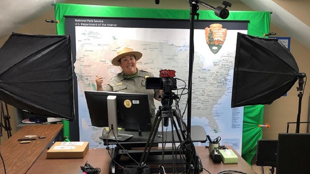 a park ranger gives a thumbs up in front of a computer and video equipment.