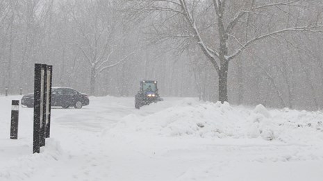 A park tractor plowing the parking area