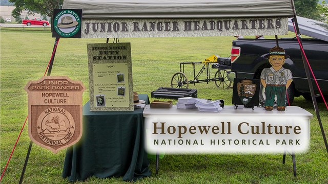 Park jr ranger badge on lower left next to a table with jr ranger activities and headquarters sign 
