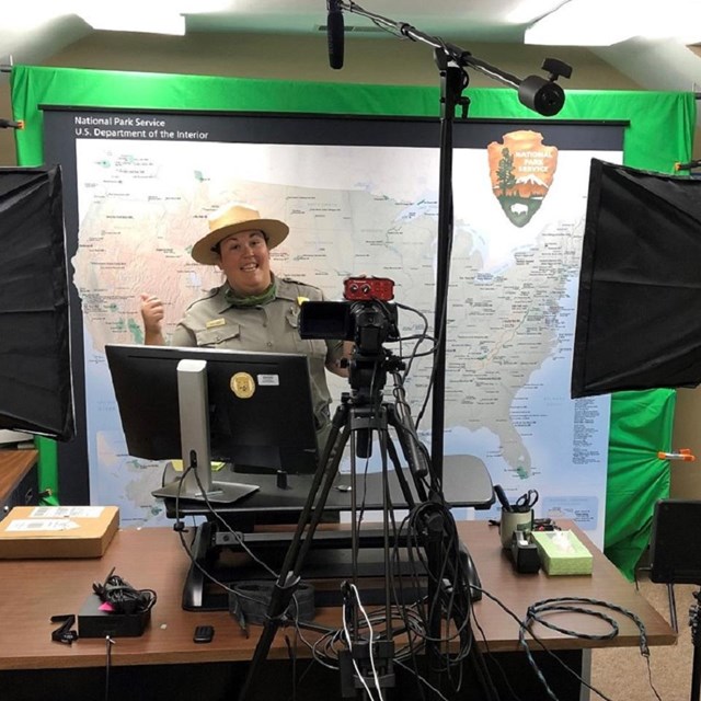 a park ranger gives a thumbs up in front of a computer and video equipment.