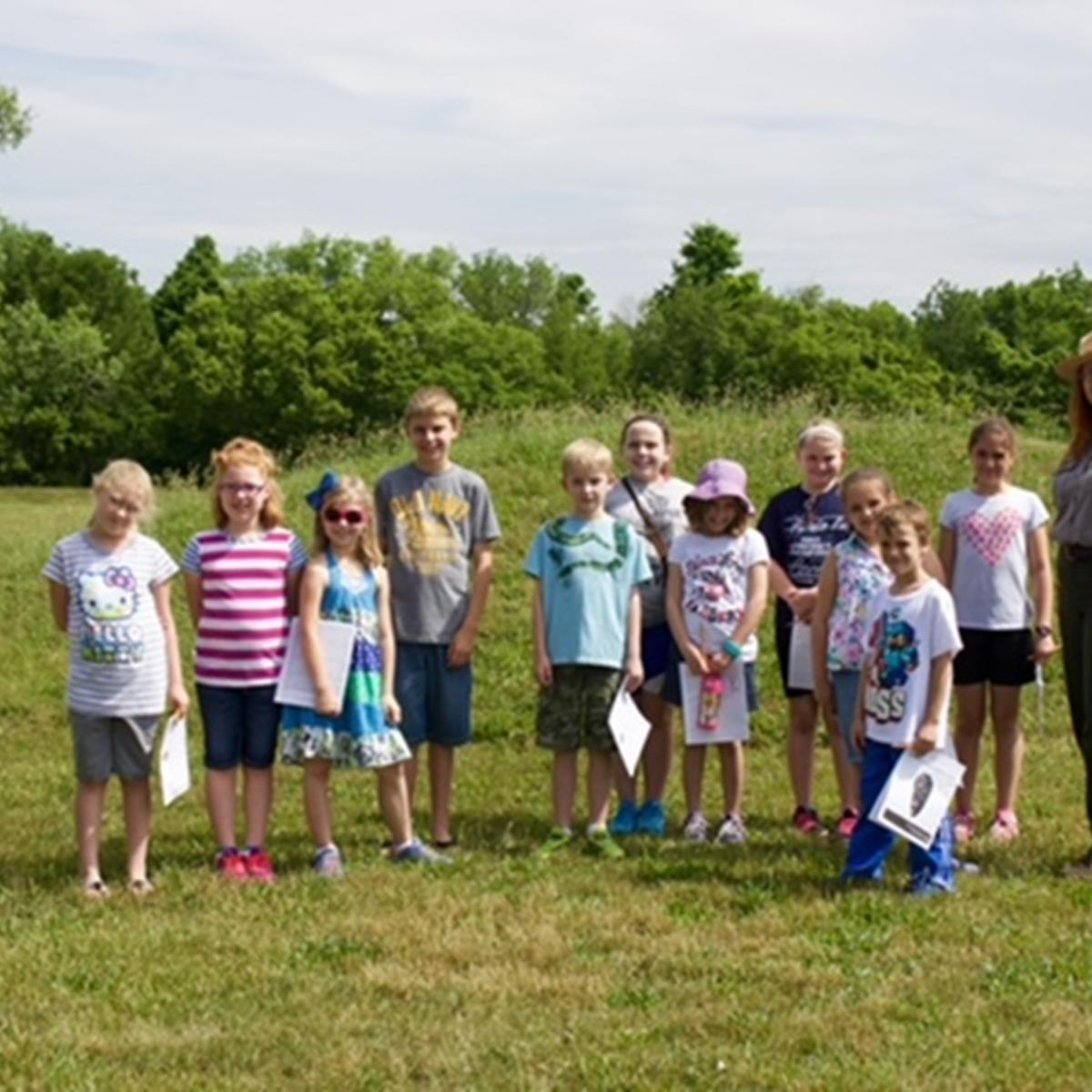 a group of children pose with a park ranger.