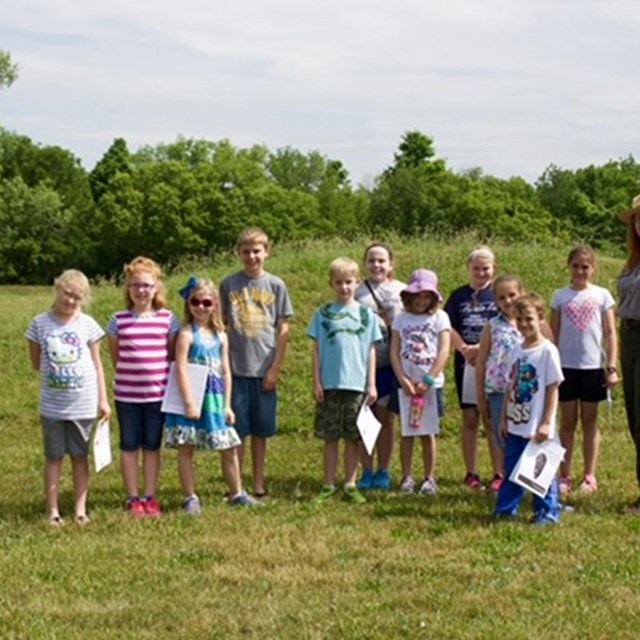 a group of children pose with a park ranger.