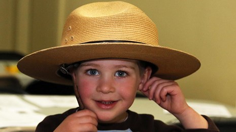 A small boy wearing a large ranger hat.