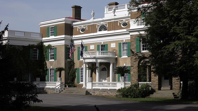 A three story stucco house with semicircular entrance portico.