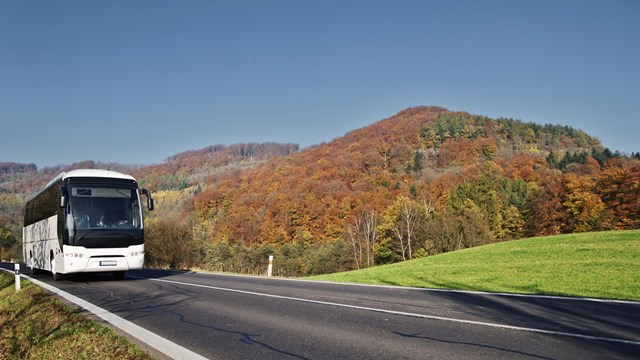 A tour bus driving through a hilly landscape.