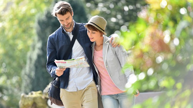 A man and woman walking arm in arm reading a map.