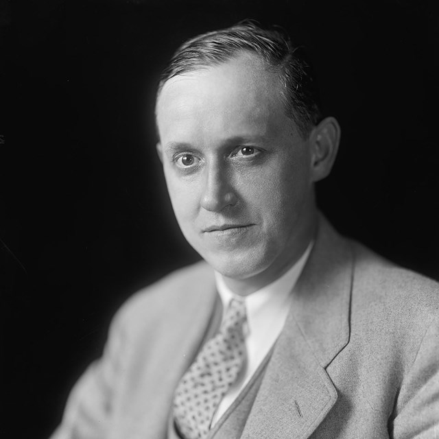 A man wearing a light suit with tie.