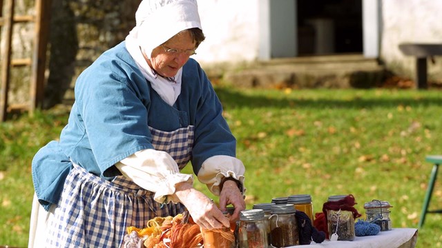 Living History volunteer organizes jars of dyed fabrics.