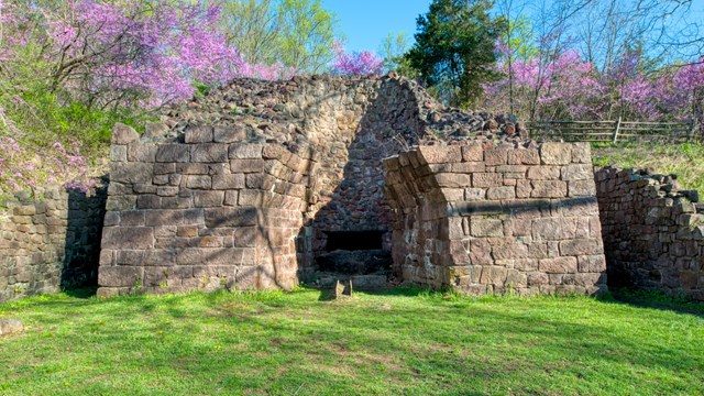 View of anthracite furnace in spring with  purple plants blooming in background.