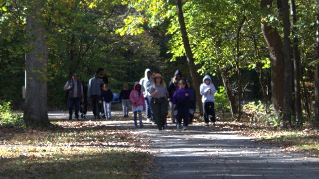 Two park rangers talk to a crowd of children. 