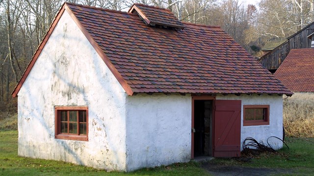 White building with red tile roof. 1 red door is visible and open. 2 red framed window is in view.