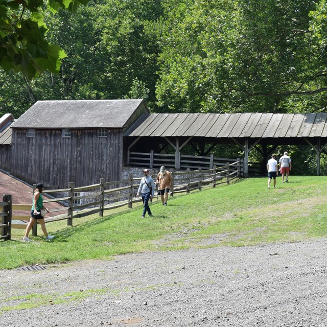 People walking back and forth between stairs and a large wooden building. 