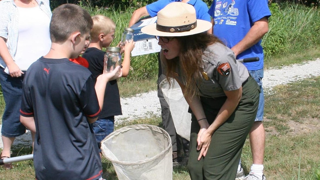 Ranger and youth look at bug in a jar