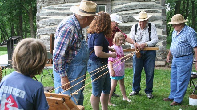Photo of volunteers showing children how to make rope.