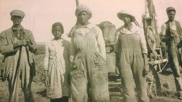 A group of people standing in front of farm equipment