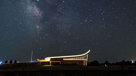 A lit building stands against a dark and starry sky.