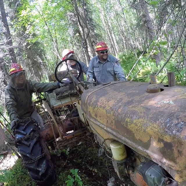 Three men pushing an old tractor