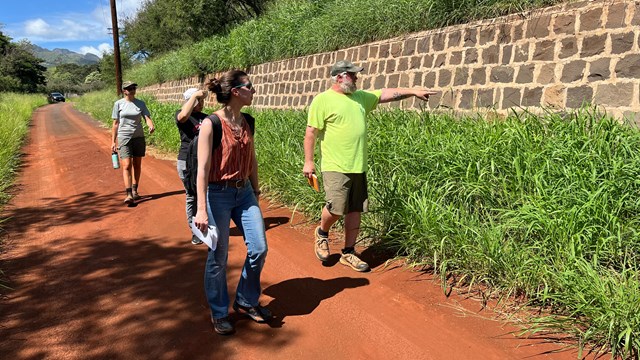 National Park Service staff talking to a group of visitors in front of a rock wall.