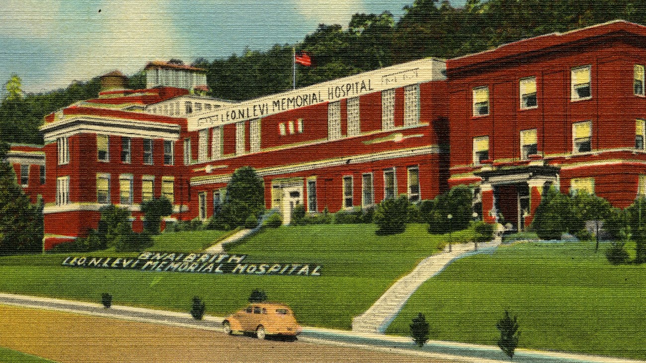 A red building on a hillside with a yellow car in front of it on the street