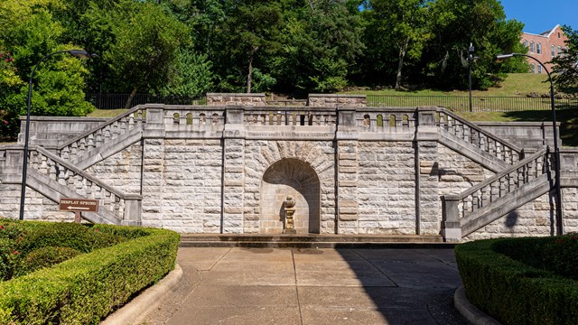 Large, wide stone staircase with a shell fountain in the center and stair entrances on the sides.