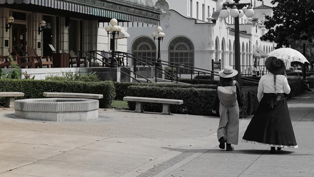 Walking down bathhouse row, 2 historical figures are seen blended into a modern day photo.