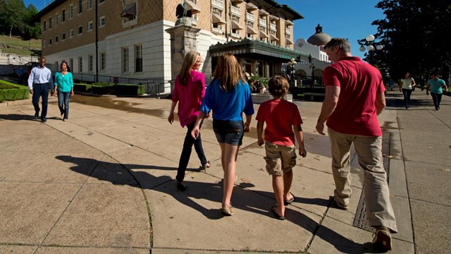 A family strolls down bathhouse row. The Fordyce Bathhouse is in the background.