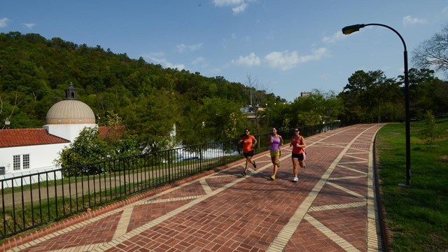 Three women running along a red brick path.