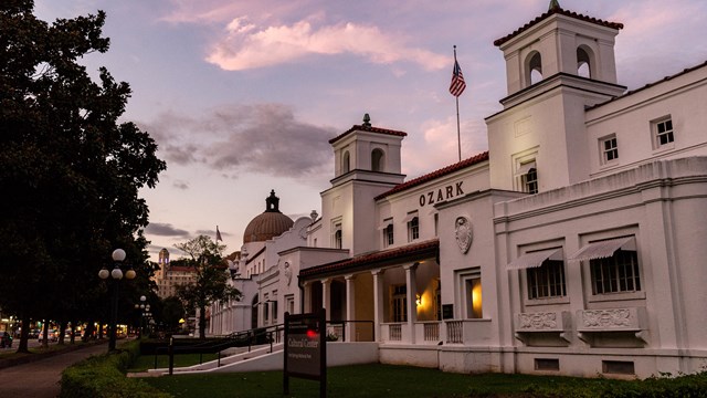 A purple sky sets behind a hacienda style, white building.