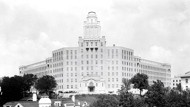 A tall looming building towers on a corner over a bathhouse. 