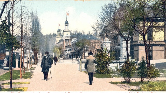 Two men walk along a sidewalk