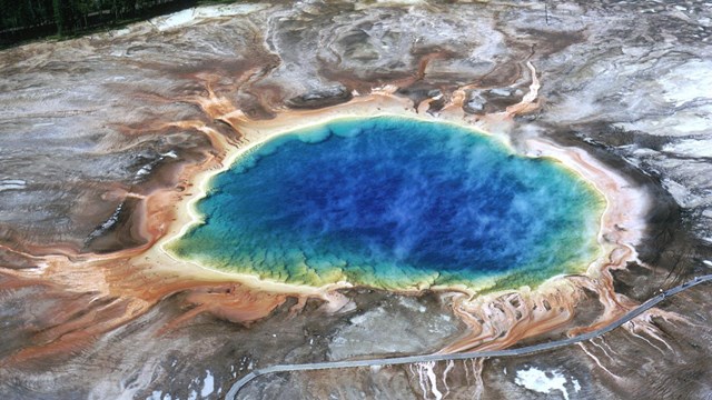 A pool of water is deep blue in the center with green, yellow, orange rings extending out.