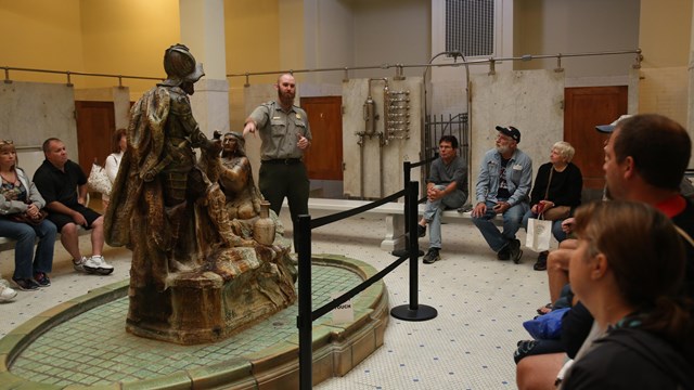 A park ranger speaks to visitors on a guided tour of a historic bathhouse