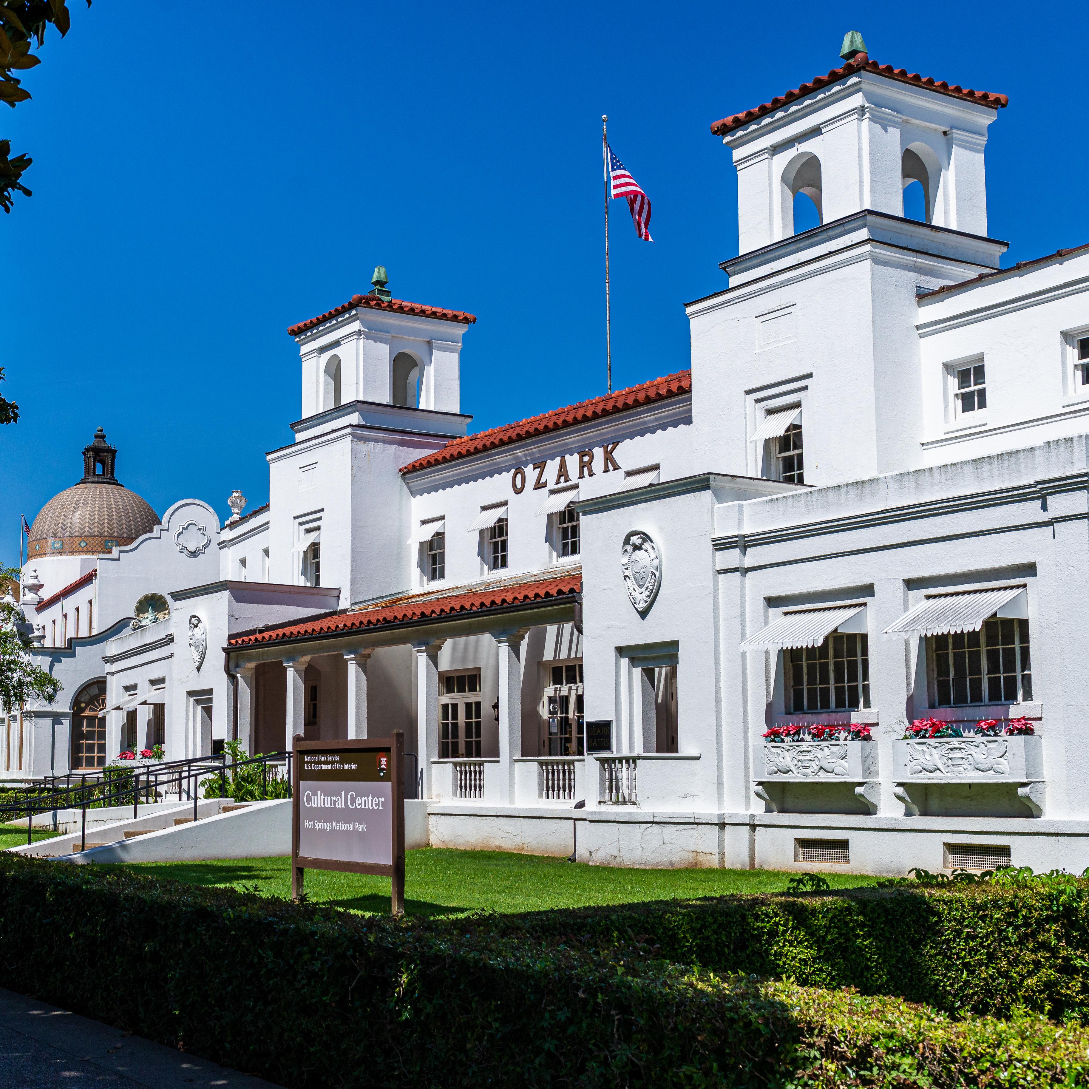 Активная сцена перед баней Фордайса; люди сидят, ходят и выглядят радостными.