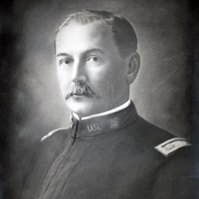 A gentleman wearing an army uniform from the late 1800s poses for a picture.