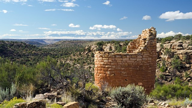 a small round stone tower perched on a cliff edge, canyon behind