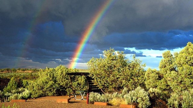 campsite with shade structure underneath a rainbow