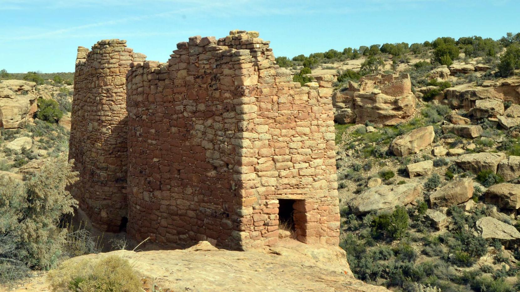 An ancestral Puebloan stone structure with a desert landscape behind it