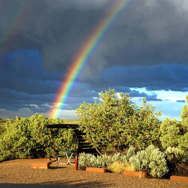 campsite with shade structure underneath a rainbow