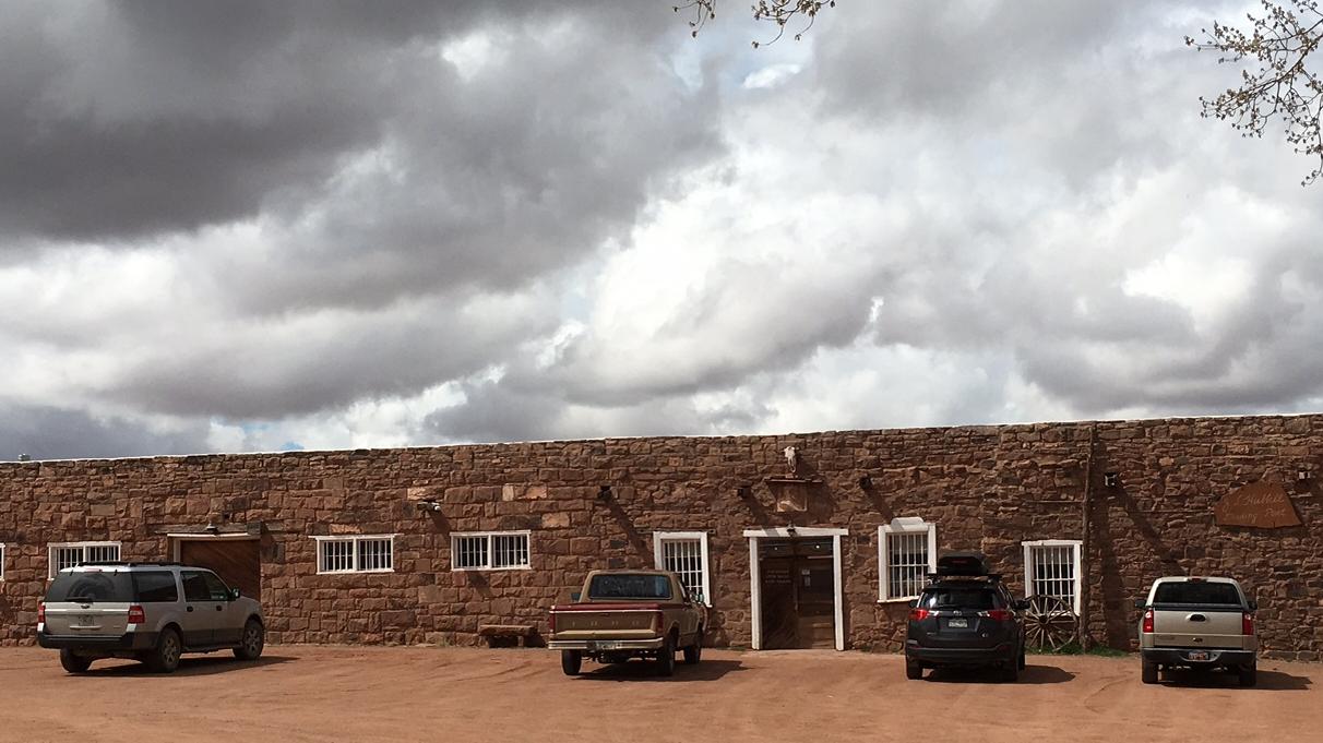 Vehicles parked in front of stone building and under cloudy skies