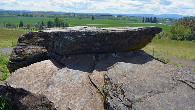 A larger flat boulder sits on top of a hill