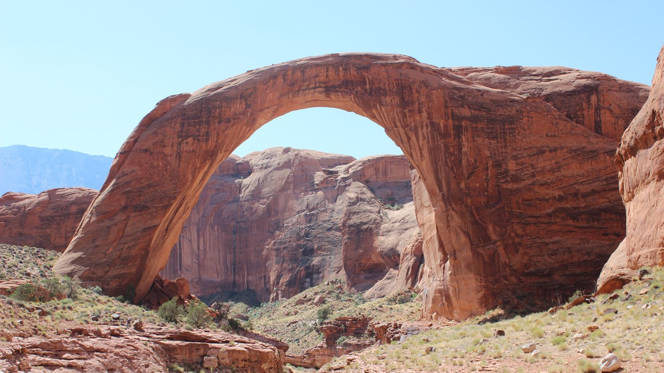 Rainbow Bridge National Monument; a massive red sandstone arch against blue sky