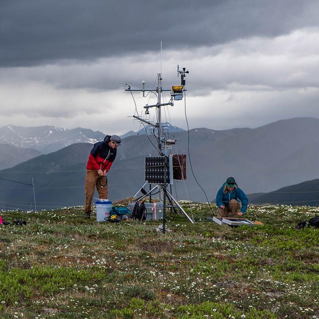 A weather station being set up on a ridge with a storm coming in.