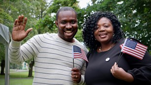 two people smiling holding small american flags