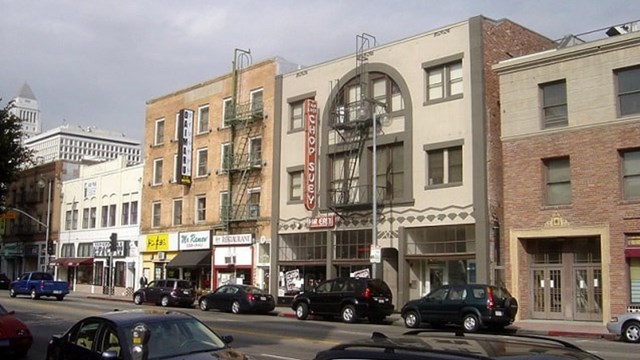 old pixelated picture of brown and gray brick buildings on a main street