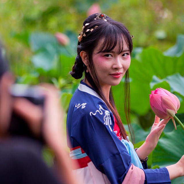 woman posing for picture holding a lotus 