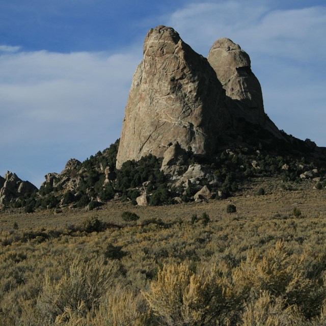 two huge rocks, the size of a building, in a field of grass