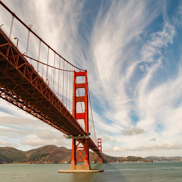 red bridge crossing water with mountains in the horizon