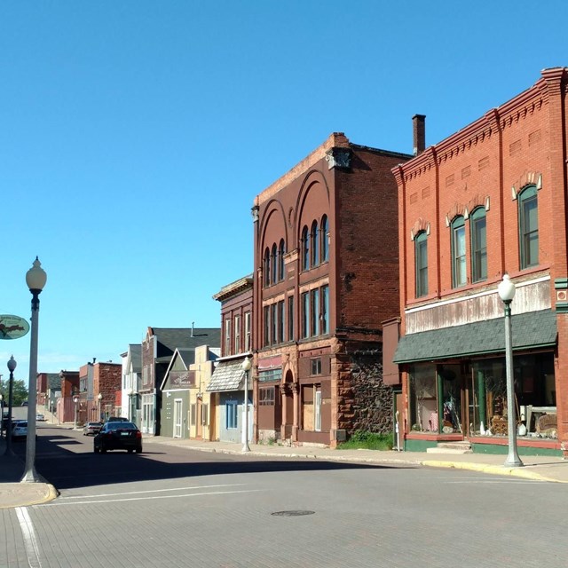 side of a paved street with brick buildings of different sizes